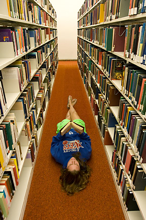 student lying down in library aisle